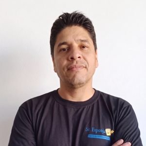 joao-carlos-tecnico-especialista-limpeza-de-estofados-sr-esponja-df Retrato de João Carlos Silva da Costa, técnico especialista em higienização de estofados, com os braços cruzados vestindo o uniforme da empresa Sr. Esponja em Brasília, DF.